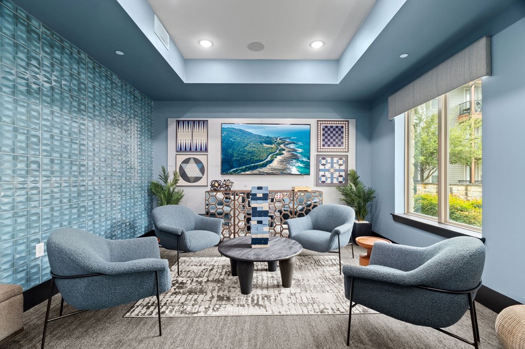 A living room with blue chairs and a large painting on the wall.