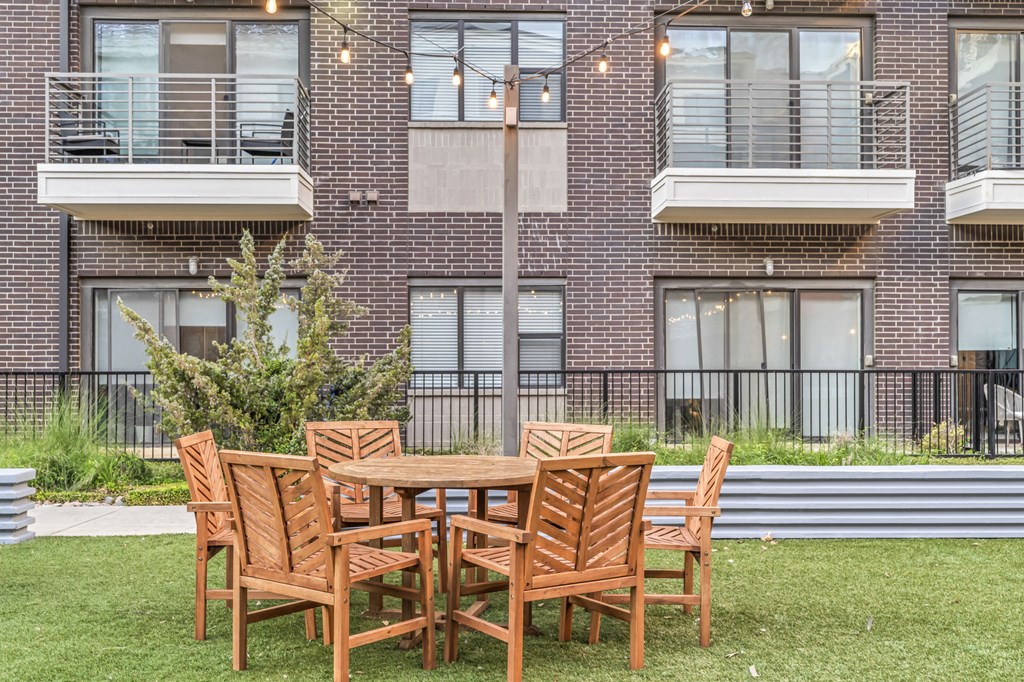 a patio with a table and chairs in front of an apartment building