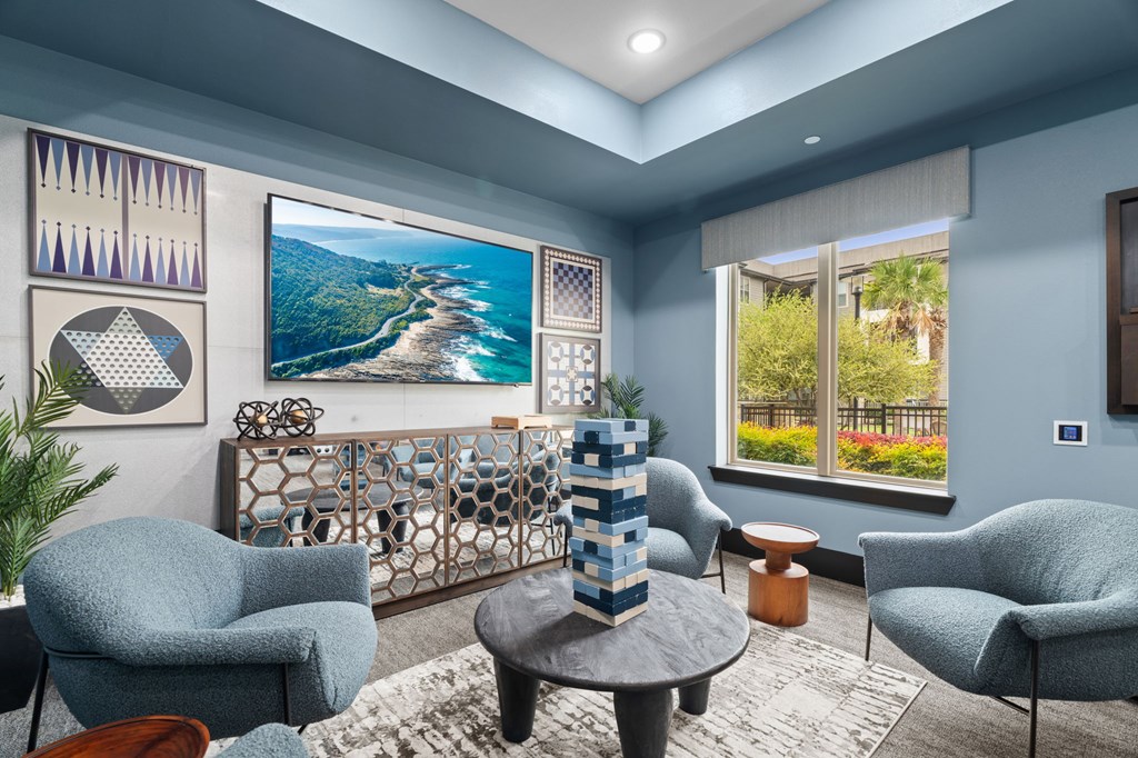 A living room with a large painting of a beach scene on the wall.