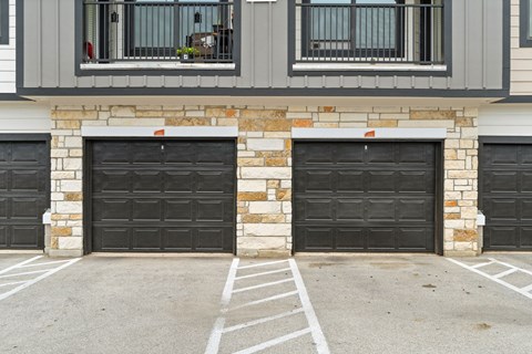 A house with two black garage doors and a stone pillar in the middle.
