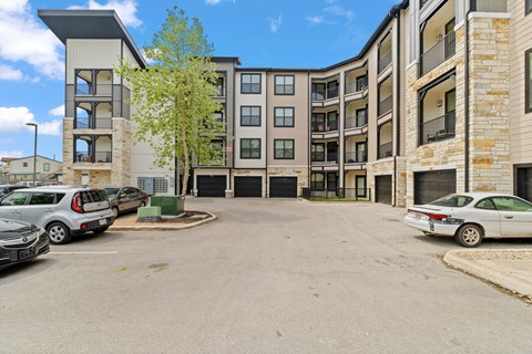 A parking lot in front of a multi-story apartment building.