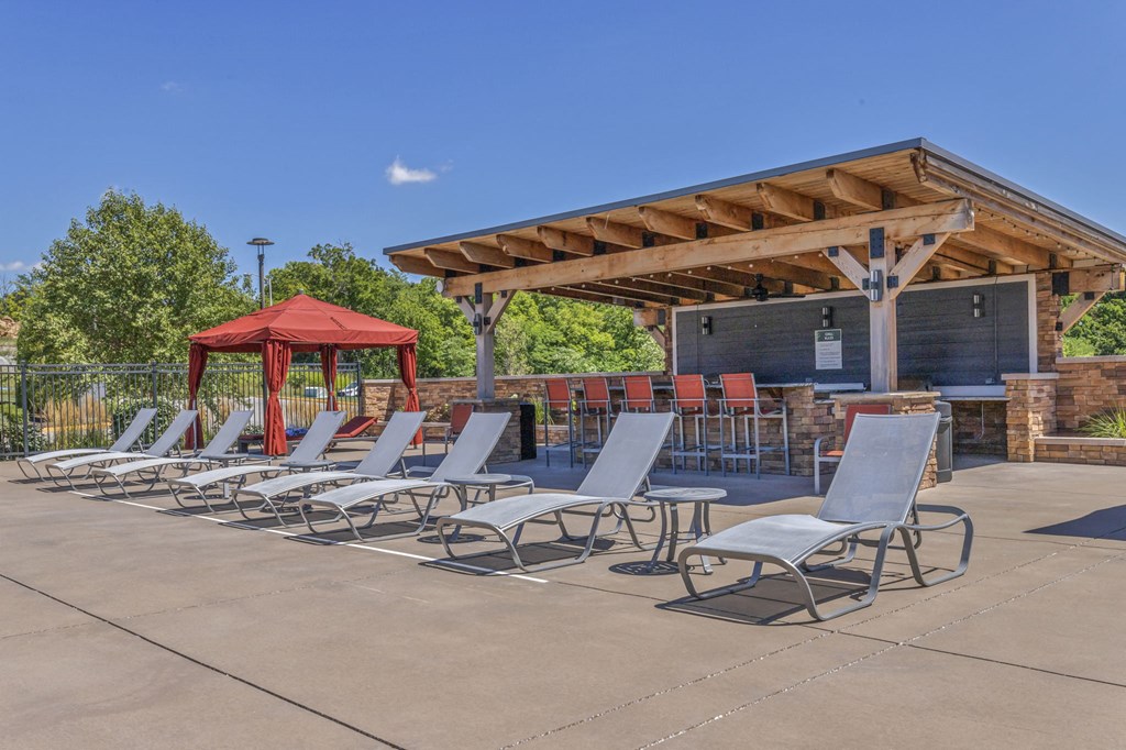 a row of lounge chairs in front of a pool with a gazebo