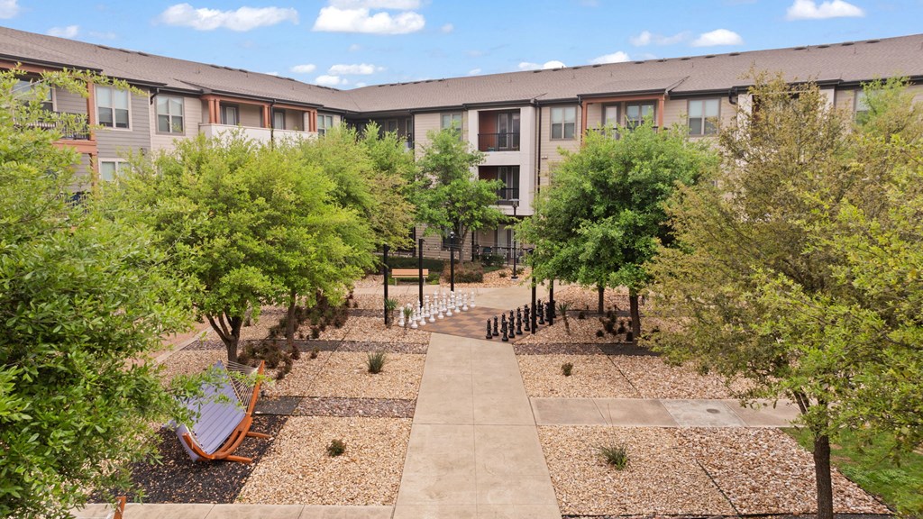 A courtyard with a bench and trees in front of apartment buildings.
