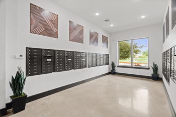 A hallway with a row of black plaques on the wall and a potted plant on the floor.