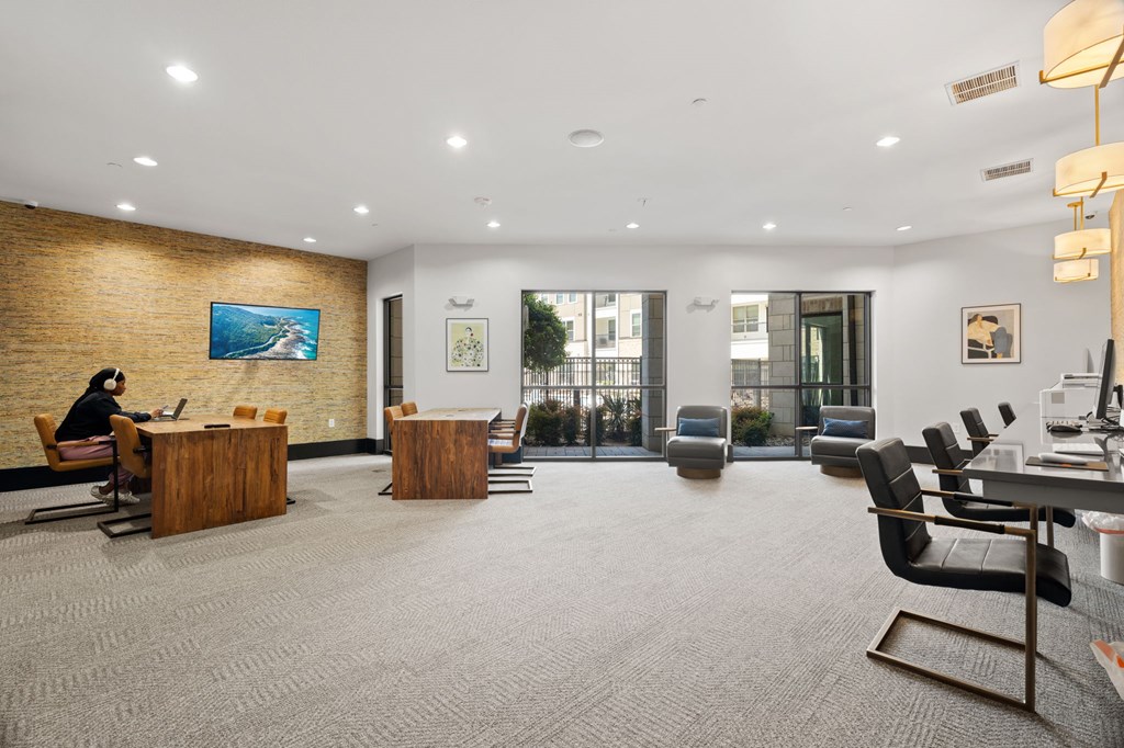 A woman is sitting at a desk in a modern office with a brick wall behind her.