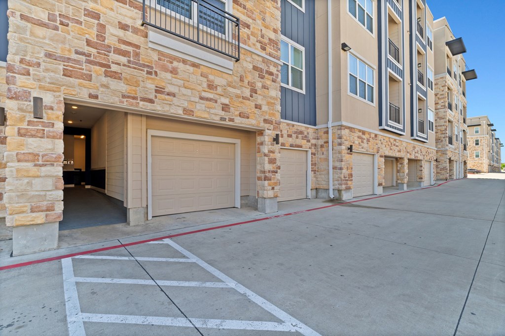 A row of garages in front of apartment buildings.