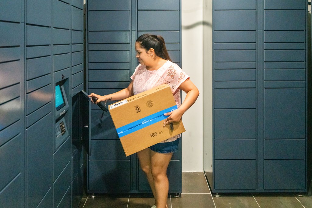 A woman is using a self-service machine with a package.