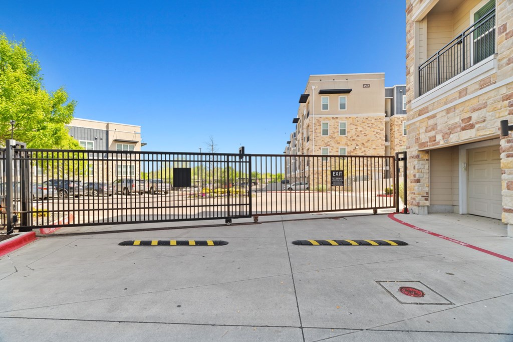 A black gate blocks the entrance to a driveway.