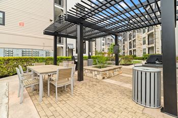 A patio with a table and chairs under a pergola.