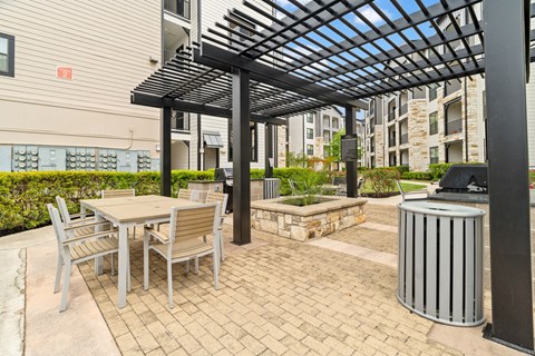 A patio with a table and chairs under a pergola.