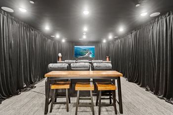 A room with a long table and chairs with a painting on the wall.