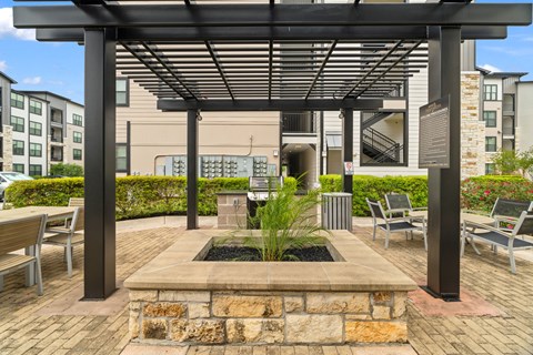 A patio with a stone wall and a pergola.