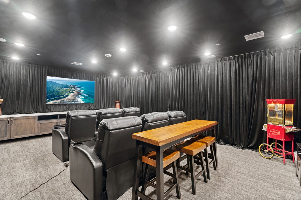 A black and white photo of a home theater with a wooden table and chairs.