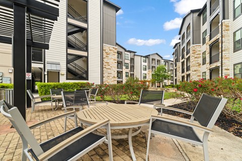 A patio with a table and chairs is surrounded by buildings.
