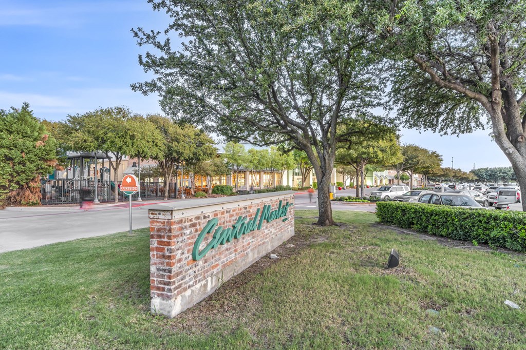 a brick sign with the name of the school in front of a parking lot with trees and