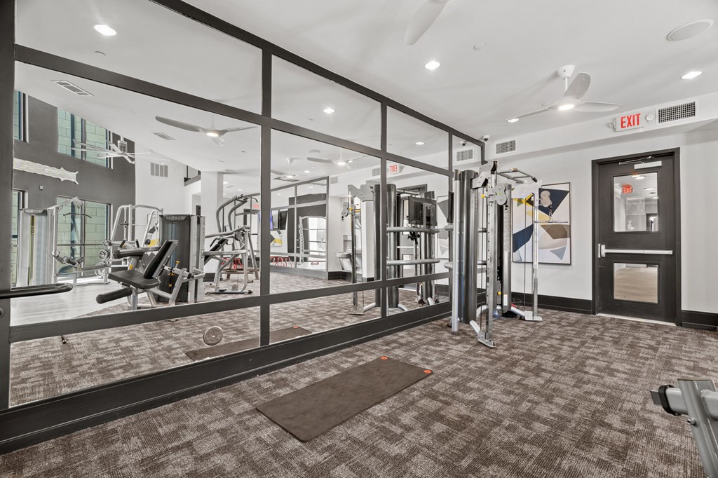 A gym with a variety of equipment and a red exit sign.