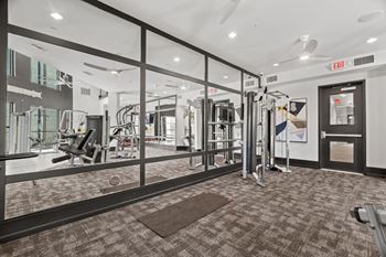 A gym with a variety of equipment and a red exit sign.