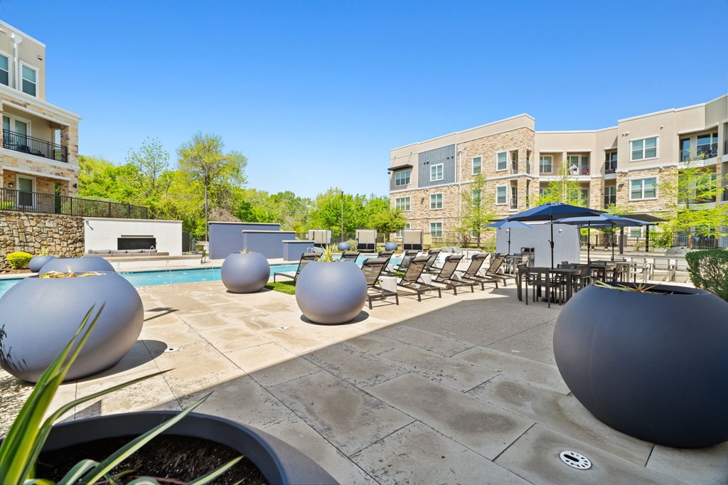 A pool area with a stone wall and a building in the background.