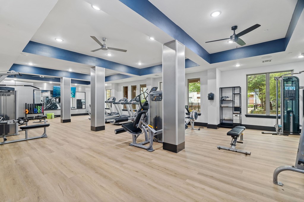 A gym with a variety of equipment including weights and cardio machines.