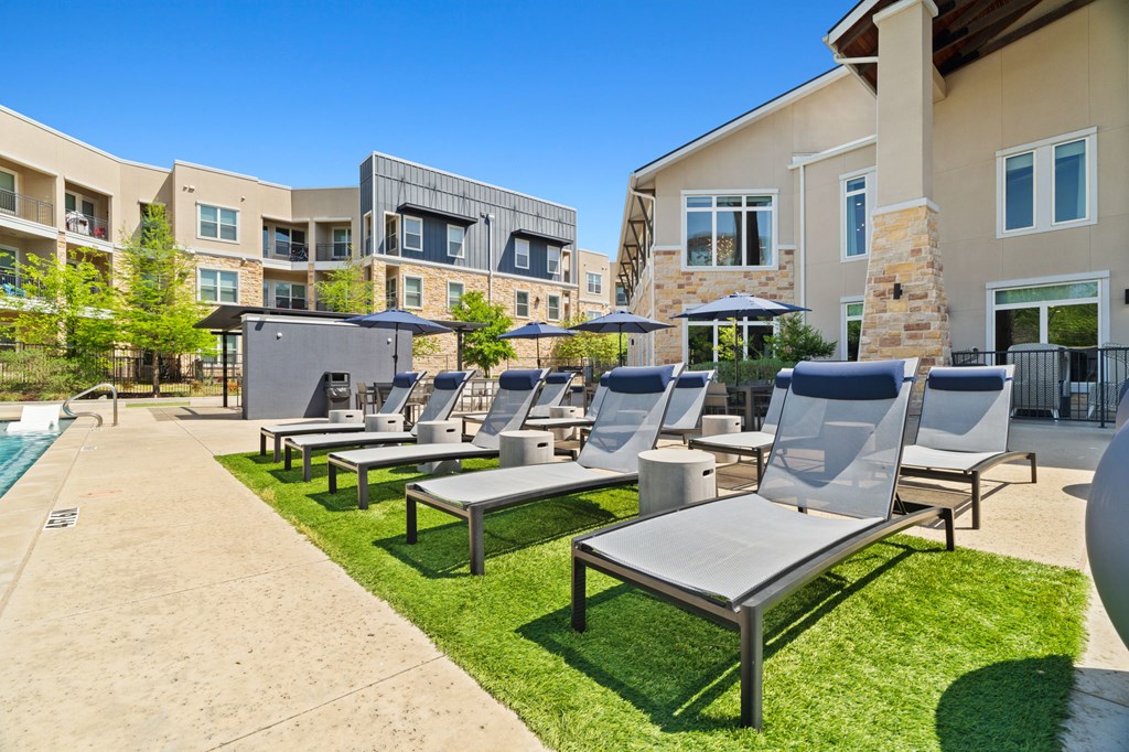 A sunny day at a resort with a pool and lounge chairs.