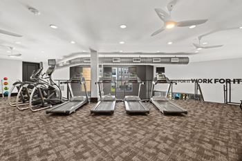 A gym with treadmills, elliptical machines, and a weight rack.