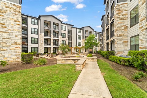 A stone pathway leads to a courtyard between two apartment buildings.