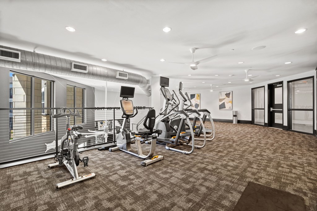 A gym with a variety of exercise equipment including treadmills, stationary bikes, and weight machines.