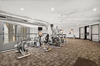 A gym with a variety of exercise equipment including treadmills, stationary bikes, and weight machines.