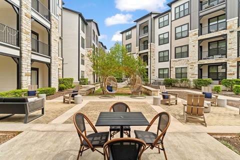 A patio with a table and chairs is surrounded by apartment buildings.