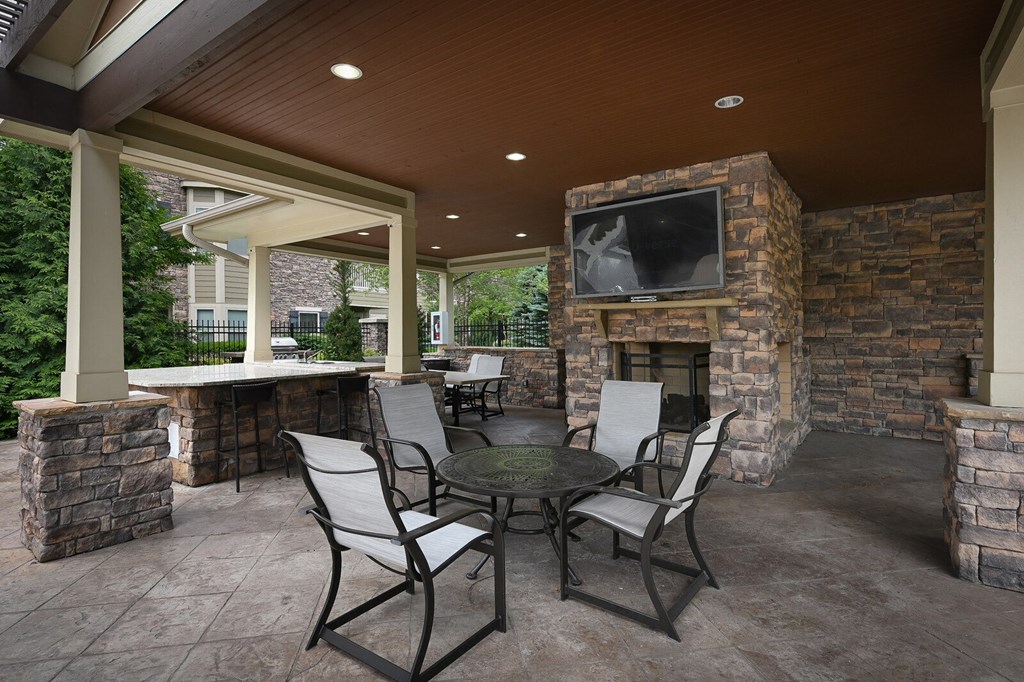 a covered patio with a table and chairs and a fireplace