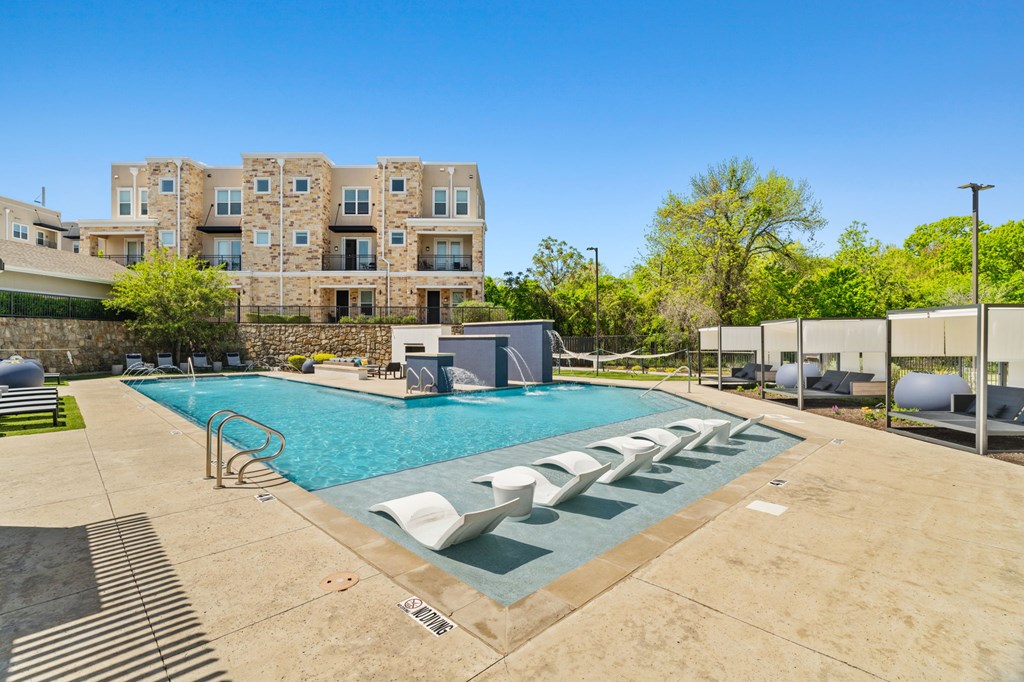 A large swimming pool in front of a multi-story apartment building.