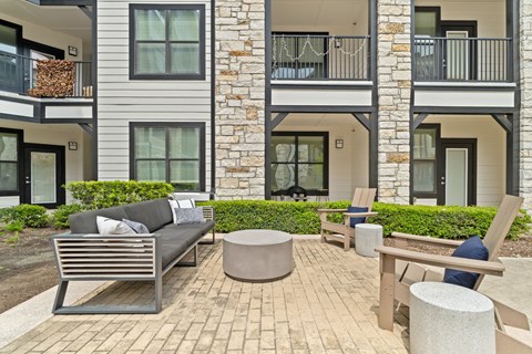 A patio with a couch, chairs, and a table in front of a building.