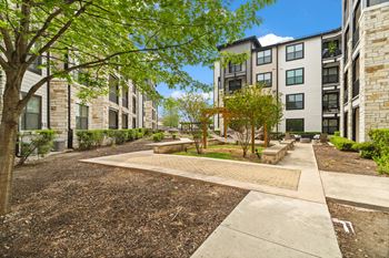 A tree-lined walkway leads to apartment buildings.