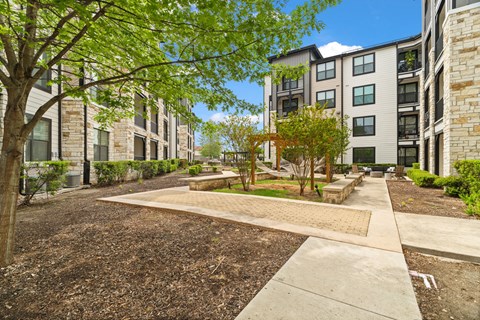 A tree-lined walkway leads to apartment buildings.