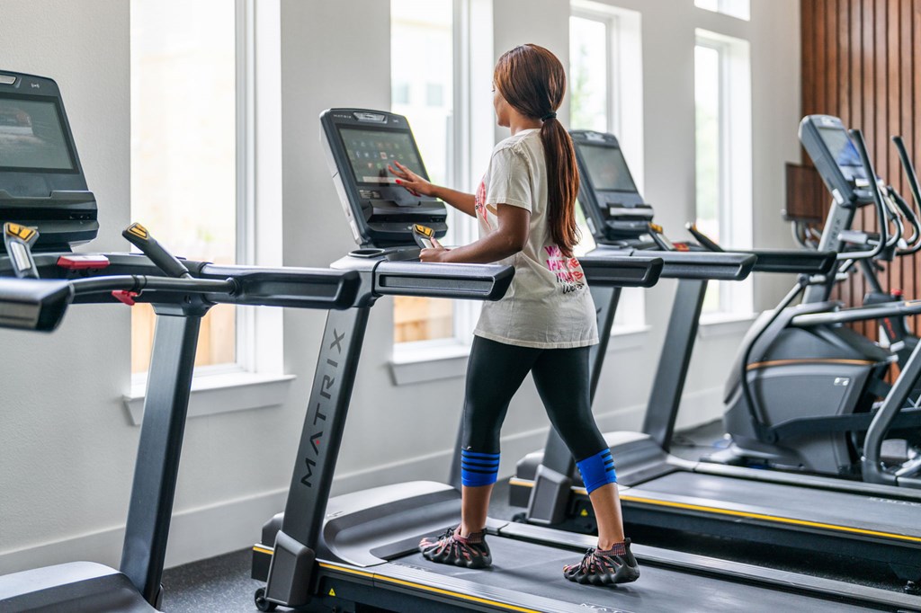 A woman is running on a treadmill in a gym.