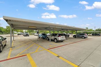A parking lot with cars parked under a shelter.