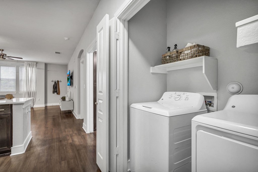 a laundry room with a washer and dryer and a hallway to a bathroom