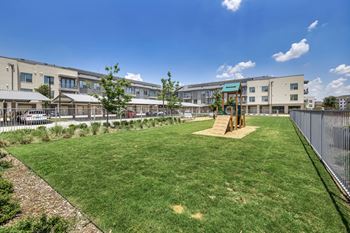 a grassy area with a swing set in front of a building