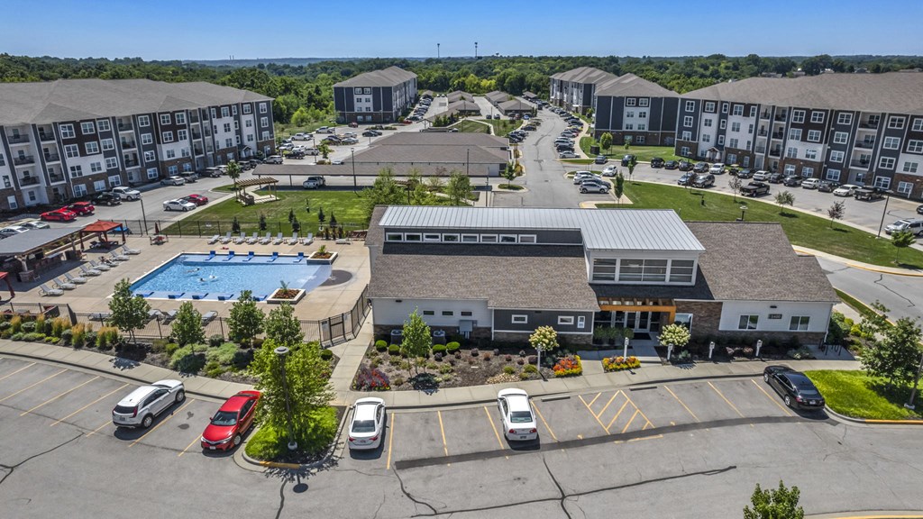 an aerial view of an apartment complex with a pool and parking lot