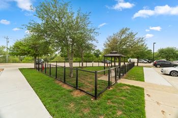 A black fence encloses a green tree and a gazebo.