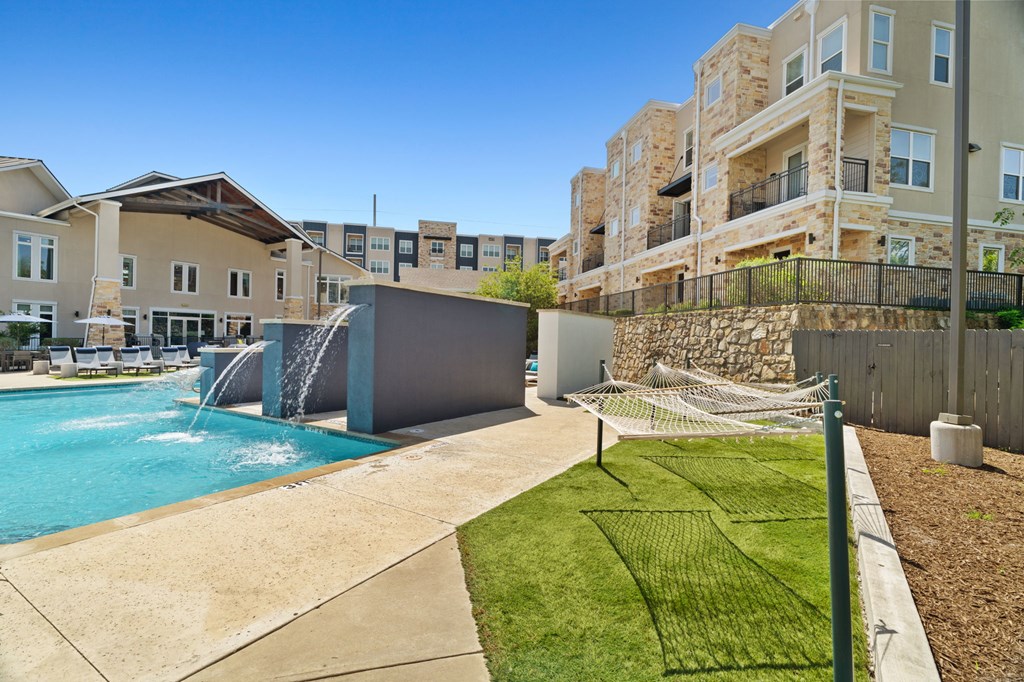 A swimming pool with a slide and a building in the background.