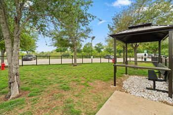 A gazebo sits in the middle of a grassy area with a picnic table and a fire hydrant.