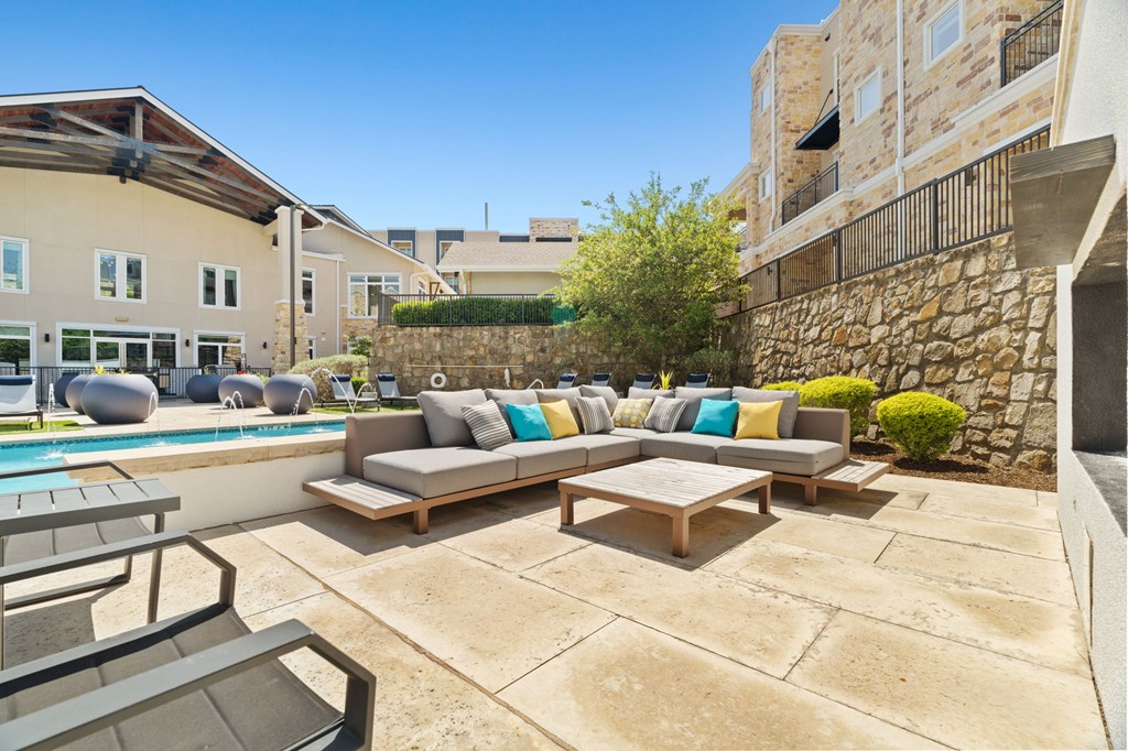 A patio with a couch and chairs overlooking a pool.
