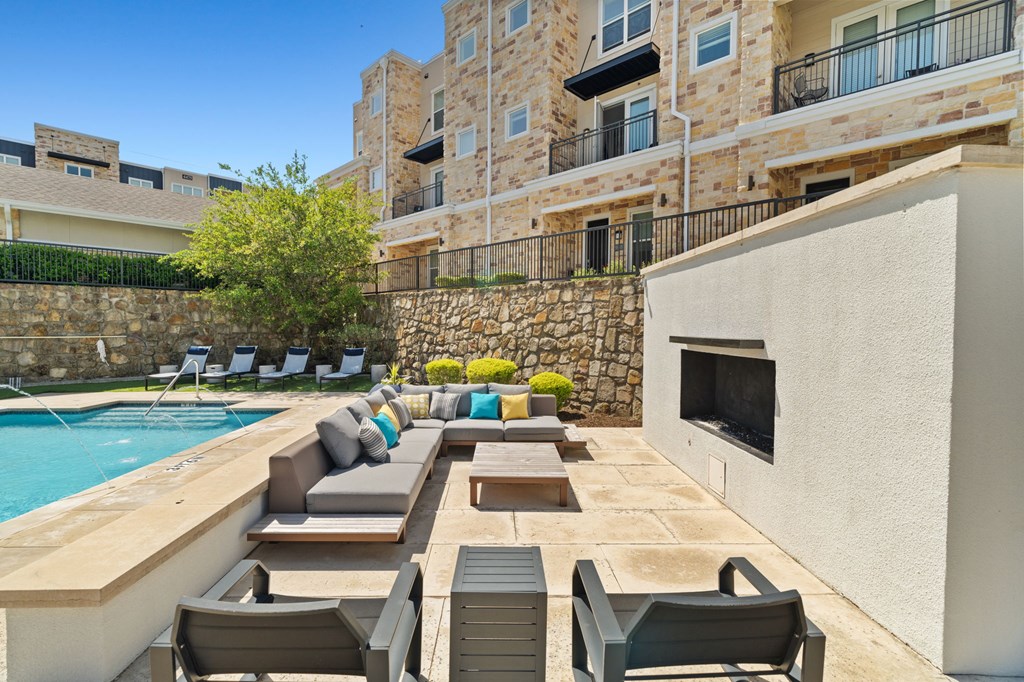 A poolside patio with chairs and a stone wall.