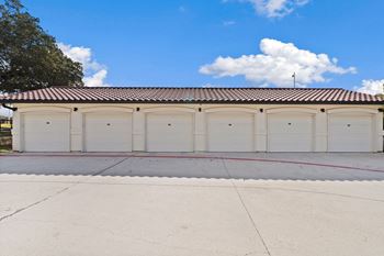 a row of garages with white doors and a red roof