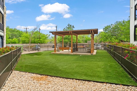 A backyard with a wooden pergola and a green lawn.