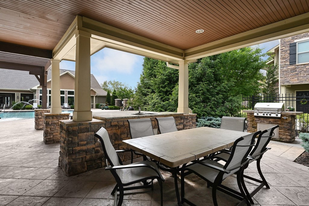 a covered patio with a table and chairs and a pool