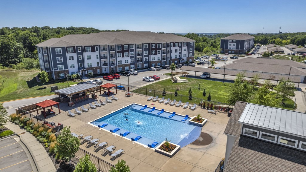 an aerial view of an outdoor swimming pool with a poolside pavilion and hotel
