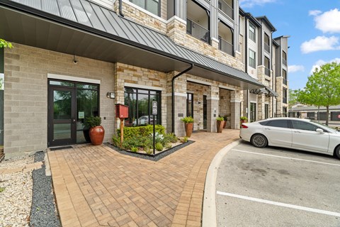 A white car is parked in front of a building with a brick facade.