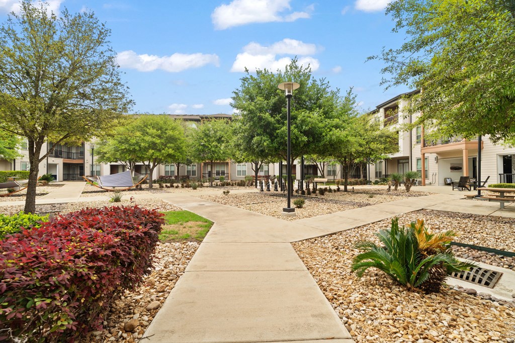 A walkway leads through a landscaped courtyard with a building in the background.